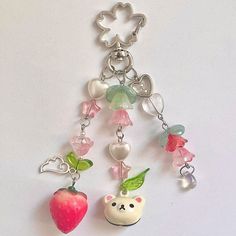 a keychain with charms attached to it on a white surface, including an apple and a bear