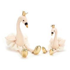 two stuffed animals dressed in white tutues and gold crowns sitting next to each other