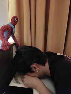 a person sleeping on a bed next to a spider man statue