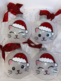 four glass christmas ornaments with cat faces on them