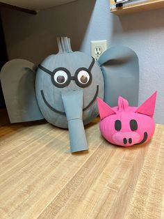 two stuffed animals sitting on top of a wooden floor next to an elephant and pig