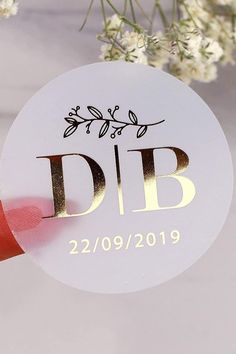 a white disc with gold lettering on it next to some flowers and red ribbon that says dib