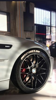 a white car parked in a garage next to another car with its wheels on the ground