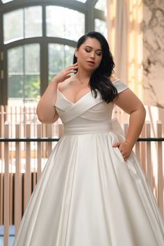 a woman in a white dress is posing for the camera with her hands on her hips