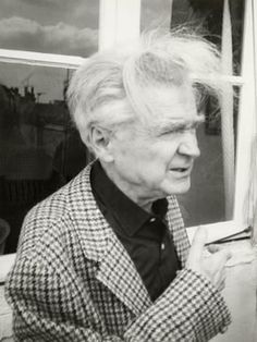 an old woman with white hair standing in front of a window