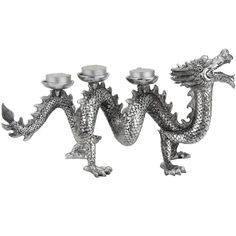 three silver dragon candlesticks are sitting on a white surface and one is holding a candle