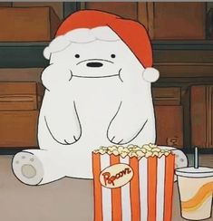 a polar bear sitting on the floor next to a box of popcorn and a drink