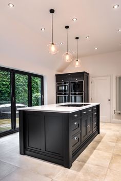 a large kitchen with an island in the middle and lots of lights hanging from the ceiling