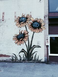 a mural on the side of a building with three sunflowers painted on it