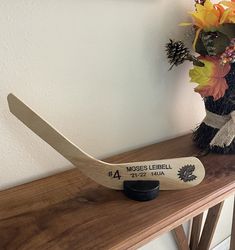 a wooden hockey stick sitting on top of a table next to a vase with flowers