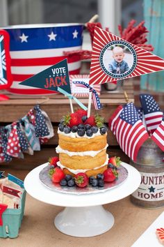 a patriotic cake with berries and strawberries on the top is surrounded by american flags