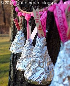 foil wrapped hot dogs hanging from a tree with pink ribbon and tags attached to them