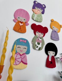 a group of felt dolls sitting on top of a white table next to a candle