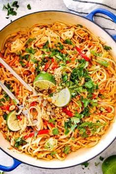 a large pot filled with noodles and garnished with cilantro, limes, and parsley