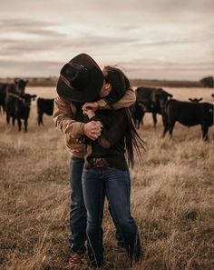 two people hugging each other in front of cows