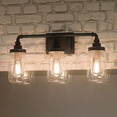 three mason jar light fixtures on a brick wall