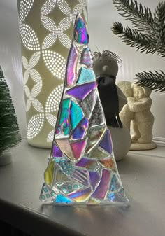 a glass christmas tree sitting on top of a table next to a potted plant