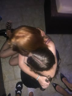 a woman in fishnet stockings is hugging another woman's head on the floor