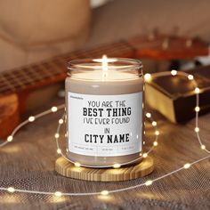 a candle sitting on top of a table next to a string of lights and a guitar