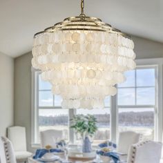 a chandelier hanging from the ceiling in a dining room with white chairs and table