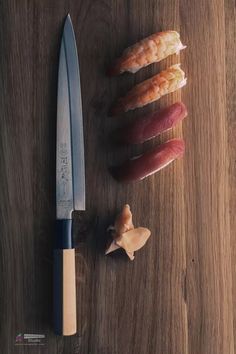 several different types of sushi on a wooden table next to a knife and chopping board