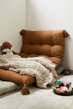 a stuffed animal laying on top of a bed in a bedroom next to a bowl of fruit