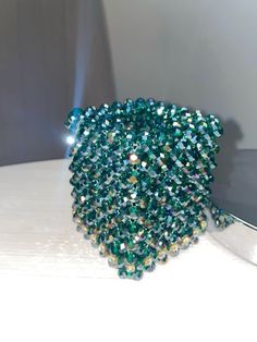 a cell phone sitting on top of a table next to a green beaded bracelet