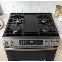 a black stove top oven sitting in a kitchen next to some spices and utensils