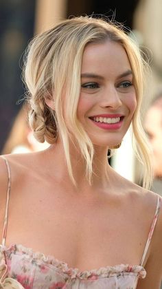 a woman with blonde hair smiling and wearing a floral dress in front of a crowd