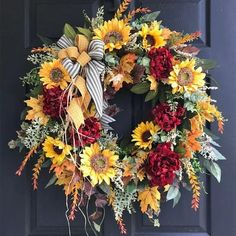 a wreath with sunflowers and other flowers is hanging on the front door,