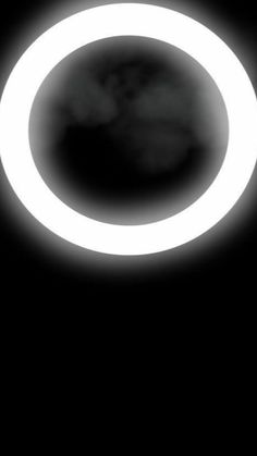 a black and white photo of a circular object in the sky with light coming from it