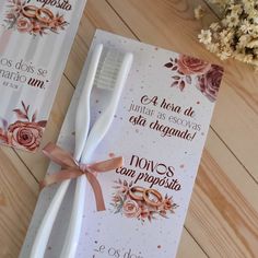 two toothbrushes with ribbons tied around them sitting on a table next to some flowers