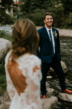 a man in a suit and tie standing next to a woman wearing a wedding dress