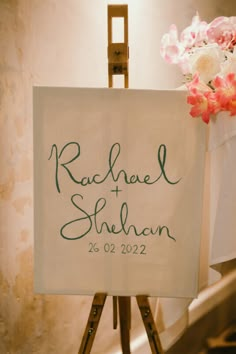 a wedding sign on a easel with flowers in the background