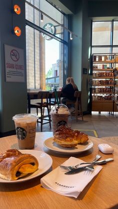 two plates with pastries on them sitting on a table in a coffee shop next to a cup of coffee