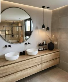 a bathroom with two sinks and a large round mirror on the wall above it's counter