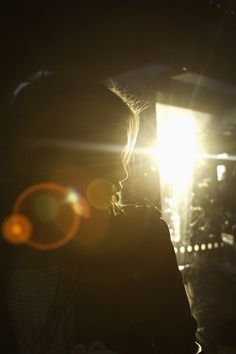 a person standing in front of a light that is shining on her face and head