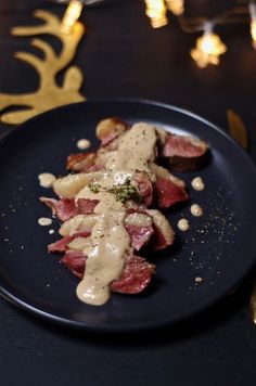 a black plate topped with meat covered in gravy