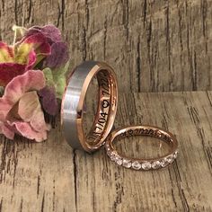 two wedding bands and one ring are sitting next to flowers