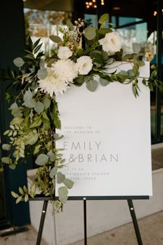 a sign with flowers and greenery on it