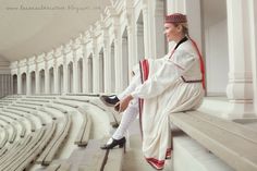 a woman sitting on top of a wooden bench next to a row of white benches