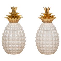 two white and gold pineapple shaped vases sitting side by side on a white background