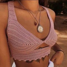 a woman wearing a pink crop top with a crochet design on the bottom