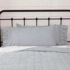 a bed with blue and white striped sheets, pillows and pillow cases on top of it