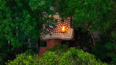 an aerial view of a fire pit in the middle of some trees with people sitting on it