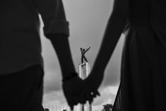 two people holding hands in front of a statue