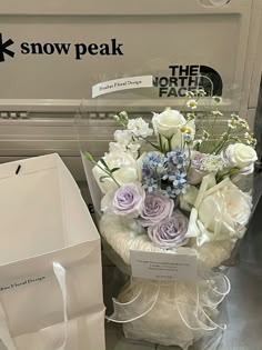 a bouquet of flowers sitting on top of a table next to a white paper bag