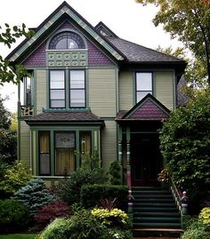 a large green house with lots of trees and bushes around it's front entrance