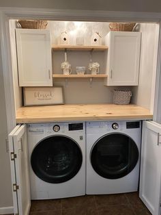 a washer and dryer in a small room with cabinets above the washer