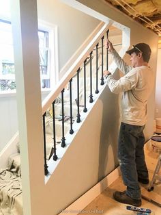 a man that is standing up against a stair case in a room with no carpet